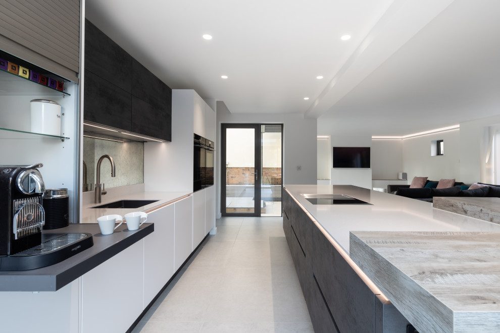 This is an example of a large contemporary single-wall kitchen/diner in Hampshire with a single-bowl sink, flat-panel cabinets, white cabinets, quartz worktops, multi-coloured splashback, mirror splashback, black appliances, ceramic flooring, an island, grey floors and white worktops.