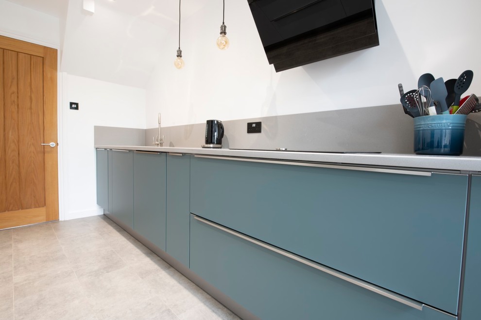 Inspiration for a medium sized modern galley kitchen/diner in Kent with a submerged sink, flat-panel cabinets, blue cabinets, quartz worktops, grey splashback, stainless steel appliances, no island, grey floors and grey worktops.