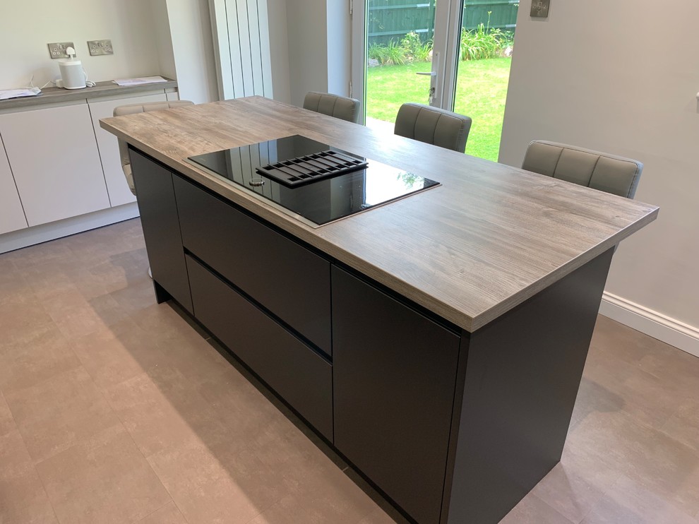 Photo of a medium sized contemporary l-shaped enclosed kitchen in Buckinghamshire with a single-bowl sink, flat-panel cabinets, laminate countertops, glass sheet splashback, integrated appliances, vinyl flooring, an island and grey floors.