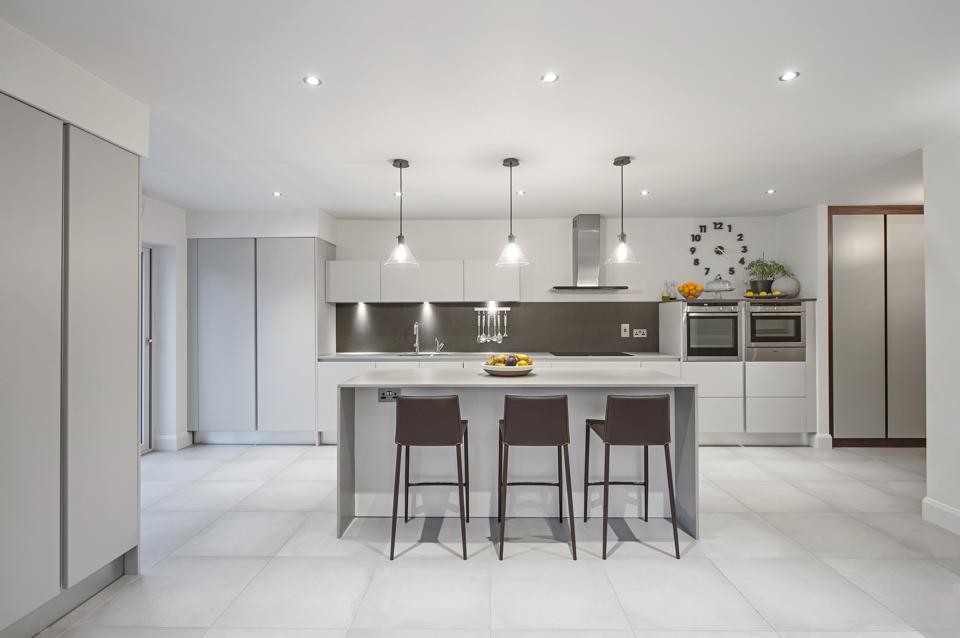 This is an example of a large contemporary galley kitchen/diner in Dublin with a submerged sink, flat-panel cabinets, grey cabinets, engineered stone countertops, grey splashback, stone slab splashback, stainless steel appliances, concrete flooring and an island.