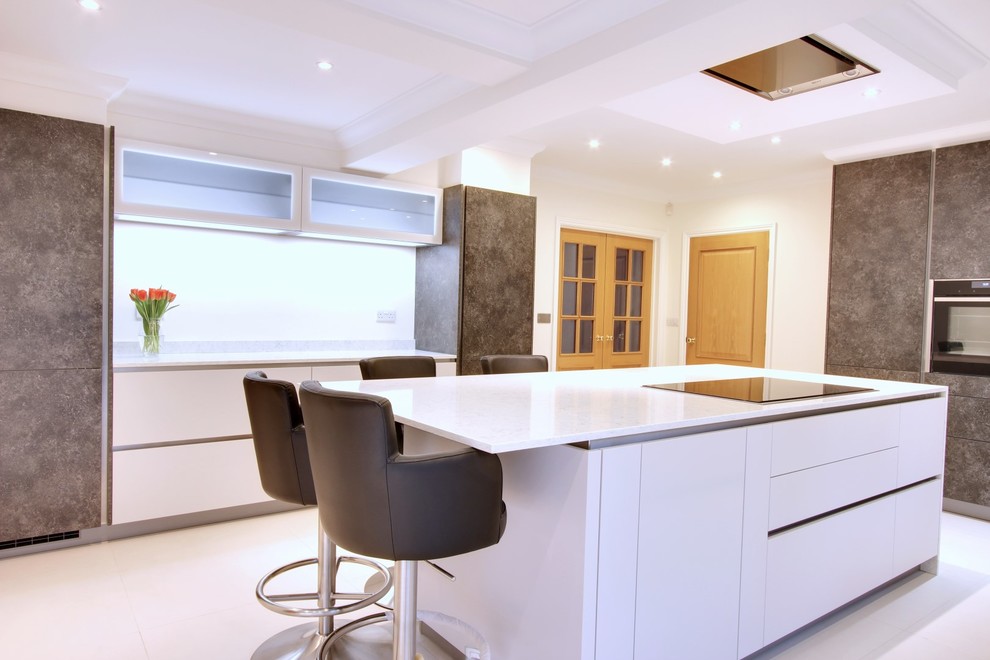 Exempel på ett mellanstort modernt kök, med en undermonterad diskho, släta luckor, vita skåp, bänkskiva i kvartsit, vitt stänkskydd, stänkskydd i sten, svarta vitvaror och en köksö