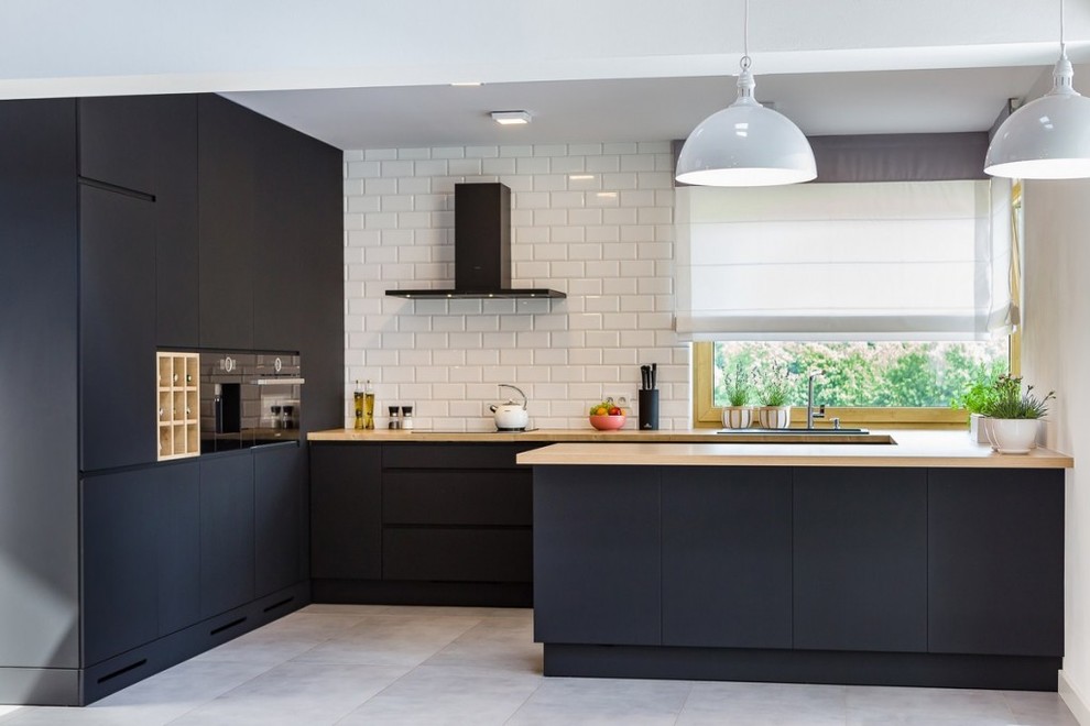 Exempel på ett modernt u-kök, med släta luckor, svarta skåp, träbänkskiva, vitt stänkskydd, stänkskydd i tunnelbanekakel, svarta vitvaror, en halv köksö och grått golv