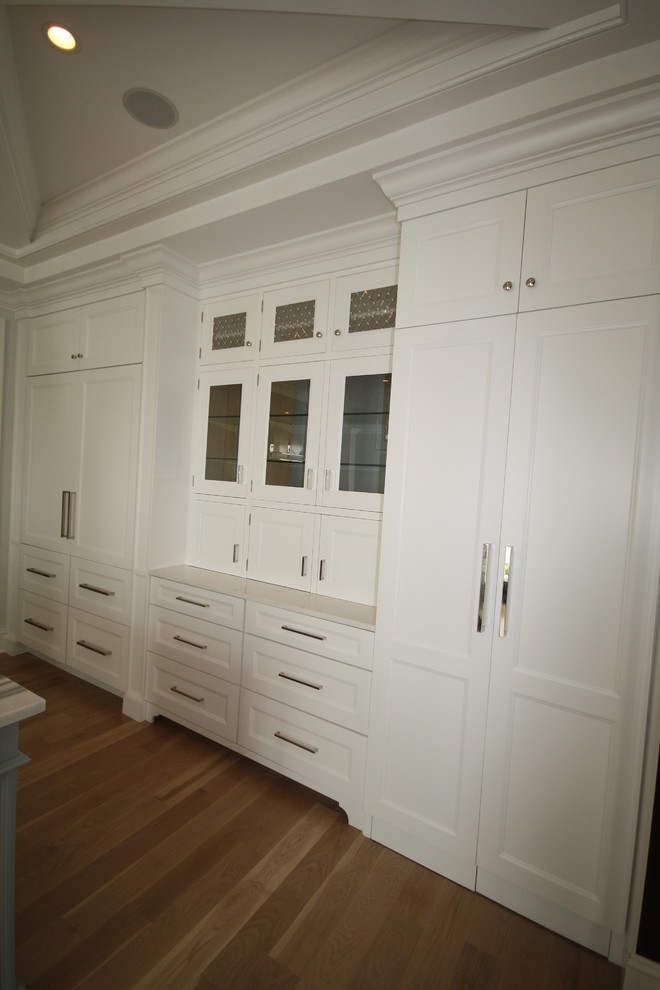 Foto de cocina tradicional renovada grande con armarios con paneles empotrados, puertas de armario blancas, suelo de madera en tonos medios, una isla y suelo marrón