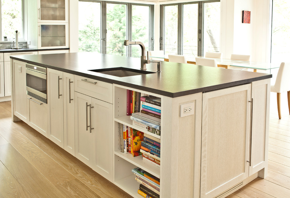 Foto de cocina contemporánea grande con fregadero bajoencimera, puertas de armario blancas, electrodomésticos de acero inoxidable, suelo de madera clara y una isla
