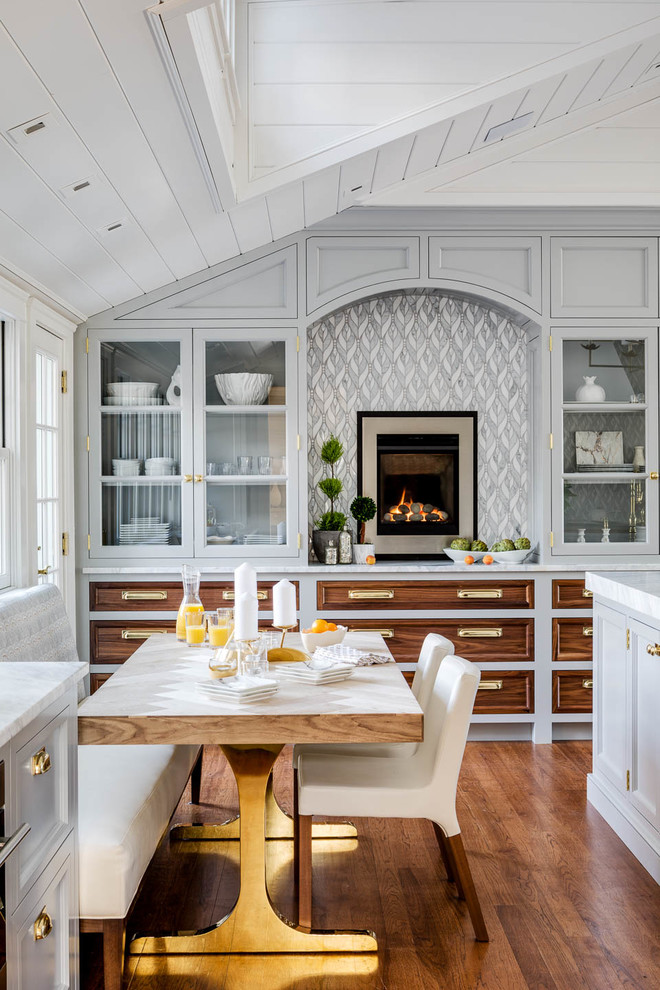 Example of a beach style medium tone wood floor and brown floor eat-in kitchen design in Providence with glass-front cabinets, gray cabinets, multicolored backsplash and white countertops