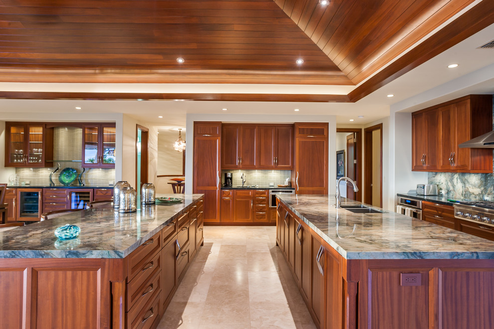 Inspiration for a large world-inspired kitchen in Hawaii with recessed-panel cabinets, quartz worktops, green splashback, glass tiled splashback, stainless steel appliances, travertine flooring and multiple islands.
