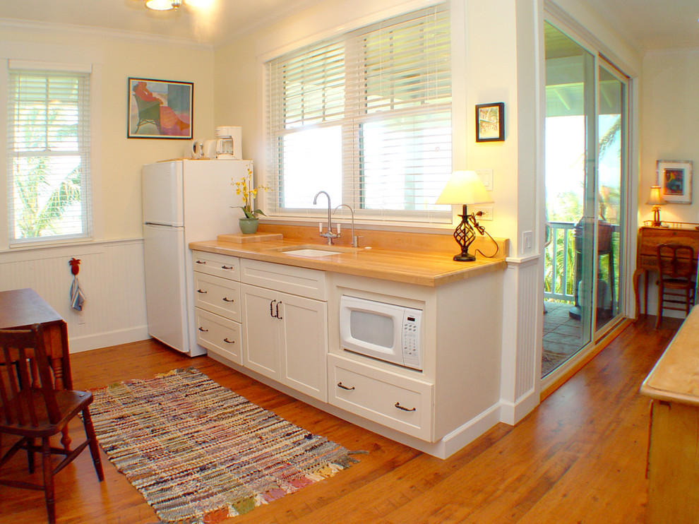 Foto di una cucina lineare tropicale con top in legno, lavello sottopiano e elettrodomestici bianchi