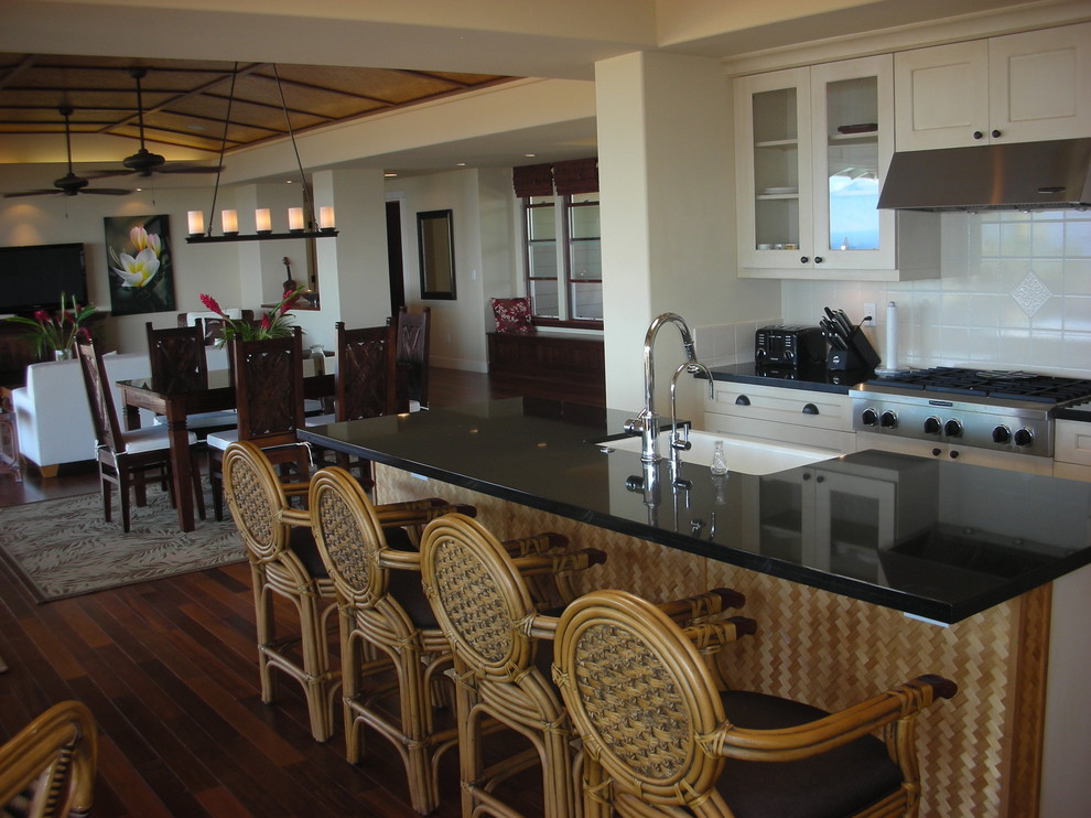 Foto di una cucina ad ambiente unico tropicale con top in granito, lavello stile country, ante di vetro, ante bianche e paraspruzzi bianco