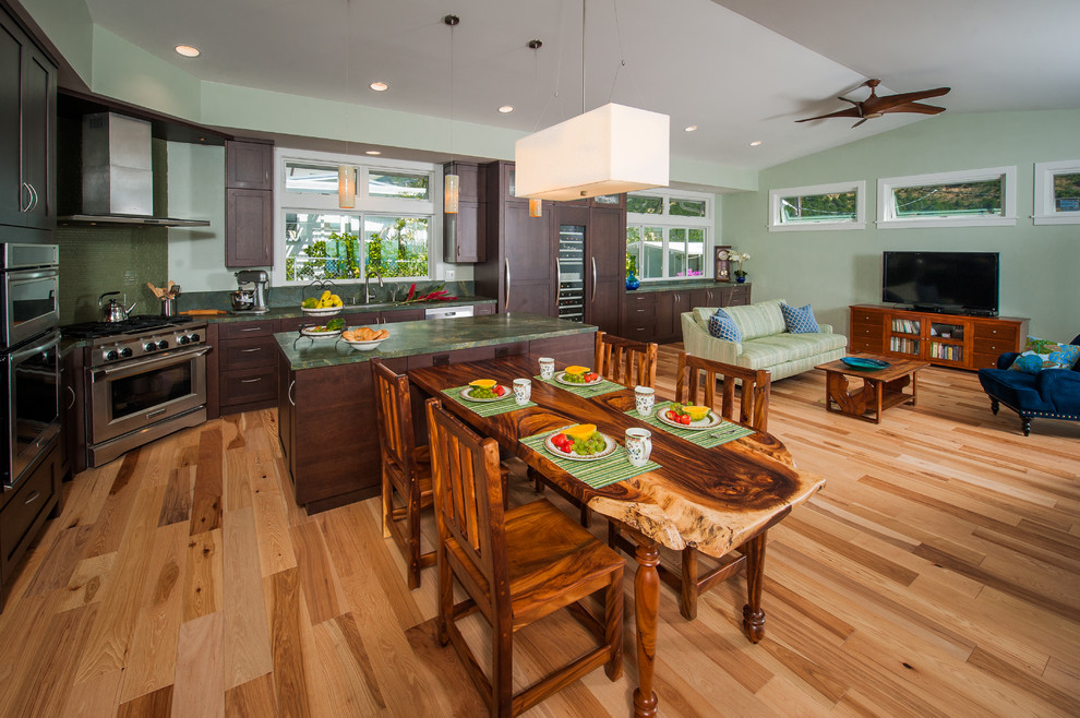 Klassische Küche in L-Form mit Unterbauwaschbecken, Schrankfronten im Shaker-Stil, dunklen Holzschränken, Granit-Arbeitsplatte, Küchenrückwand in Grün, Glasrückwand, Elektrogeräten mit Frontblende, hellem Holzboden und Kücheninsel in Hawaii
