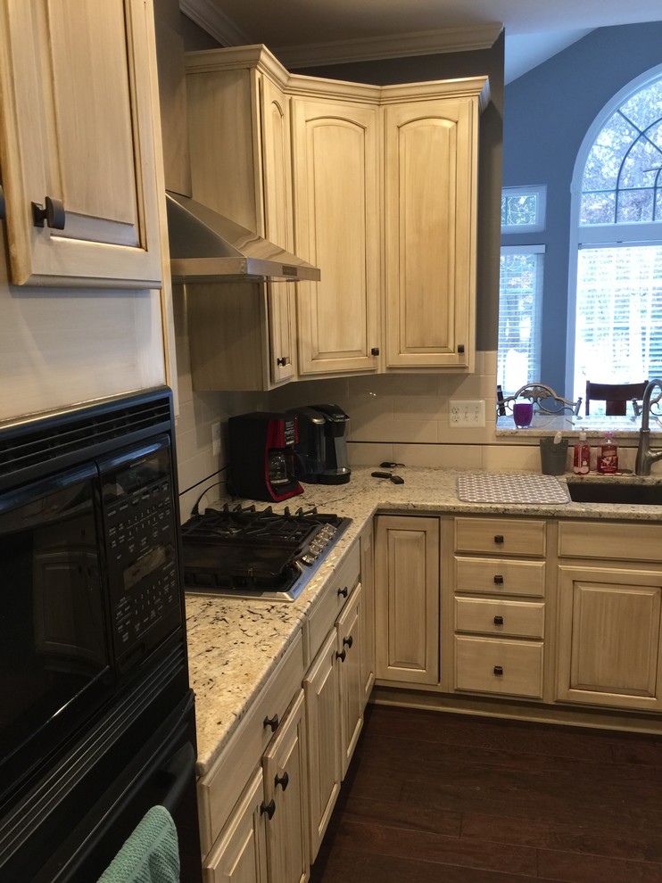 Idéer för att renovera ett mellanstort vintage grå grått kök, med en undermonterad diskho, luckor med upphöjd panel, vita skåp, granitbänkskiva, svarta vitvaror, mörkt trägolv, en köksö och brunt golv