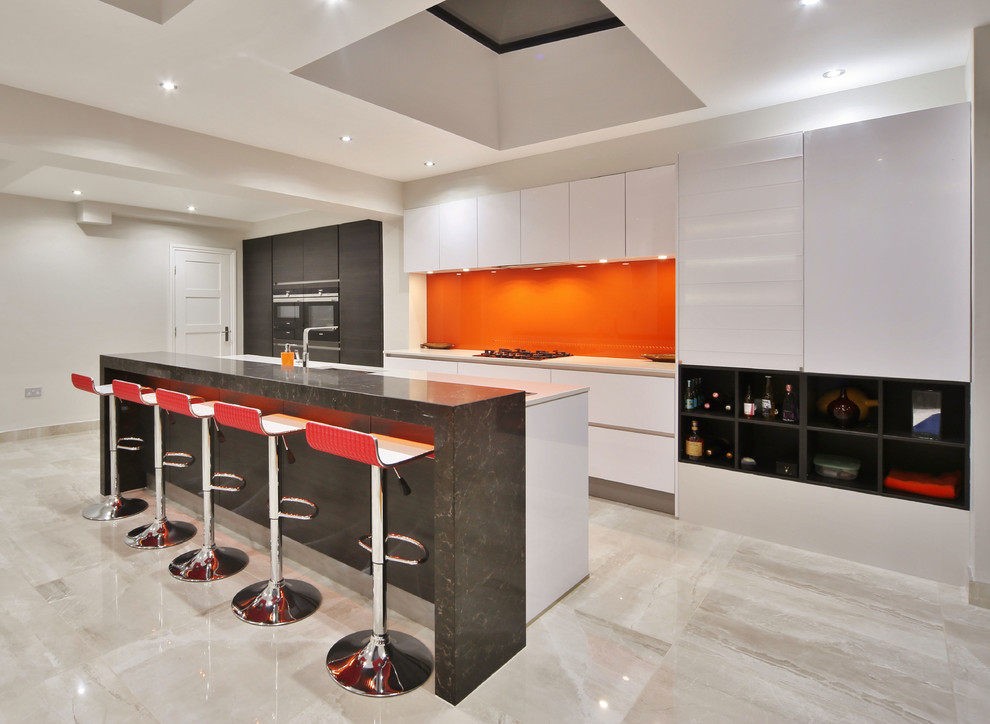 This is an example of a medium sized contemporary galley kitchen in London with a submerged sink, flat-panel cabinets, white cabinets, quartz worktops, orange splashback, glass sheet splashback, black appliances, porcelain flooring, an island, beige floors and white worktops.