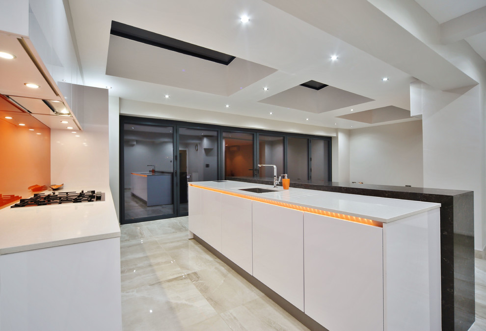 Immagine di una cucina design di medie dimensioni con lavello sottopiano, ante lisce, ante bianche, top in quarzite, paraspruzzi arancione, paraspruzzi con lastra di vetro, elettrodomestici neri, pavimento in gres porcellanato, pavimento beige e top bianco