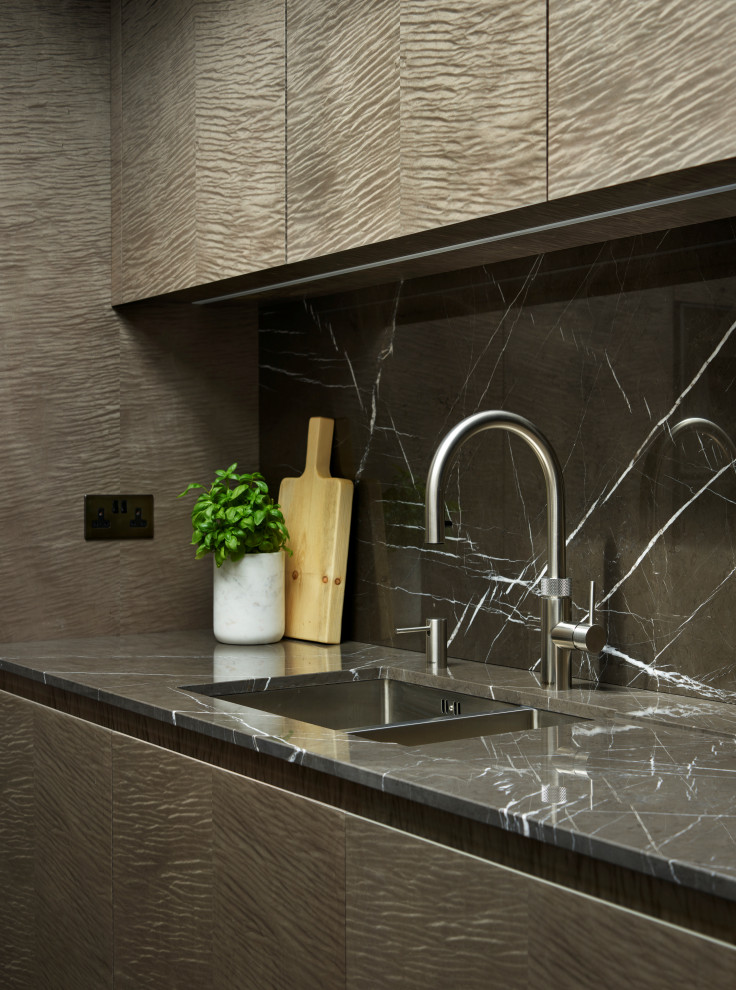 Immagine di una cucina minimalista di medie dimensioni con lavello integrato, ante lisce, ante in legno chiaro, top in marmo, penisola e top marrone