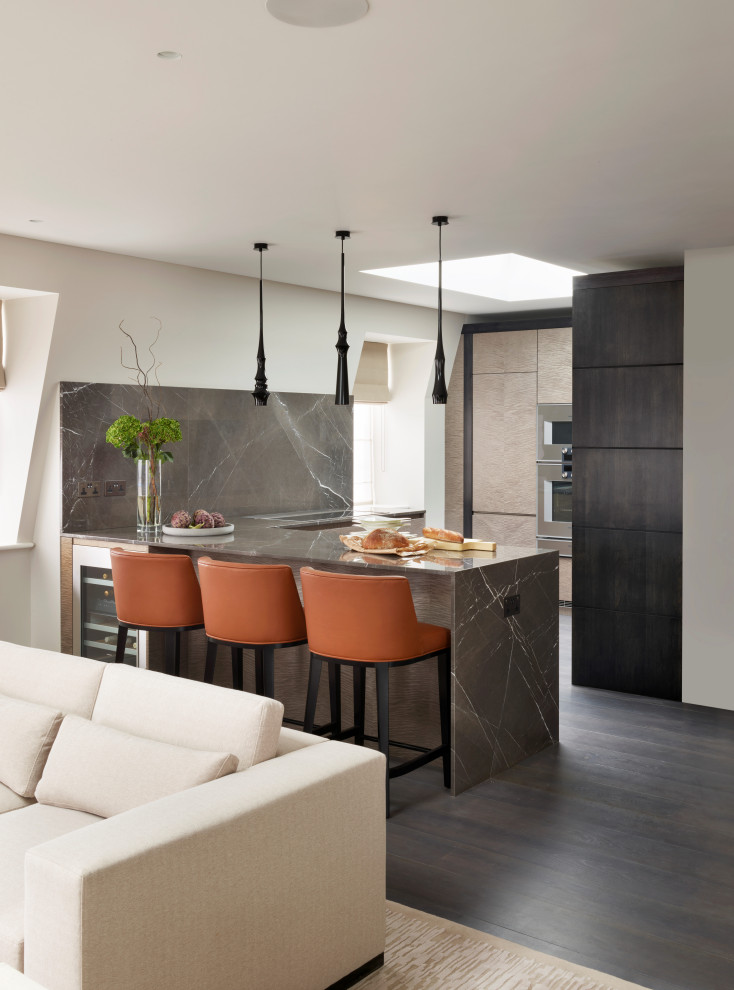 Стильный дизайн: параллельная кухня-гостиная среднего размера в стиле модернизм с монолитной мойкой, плоскими фасадами, светлыми деревянными фасадами, мраморной столешницей, полуостровом и коричневой столешницей - последний тренд