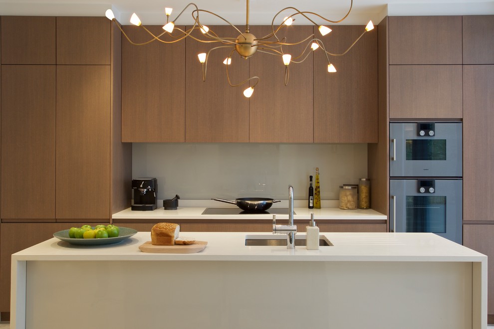 Medium sized contemporary kitchen in London with a submerged sink, flat-panel cabinets, glass sheet splashback, an island and medium wood cabinets.