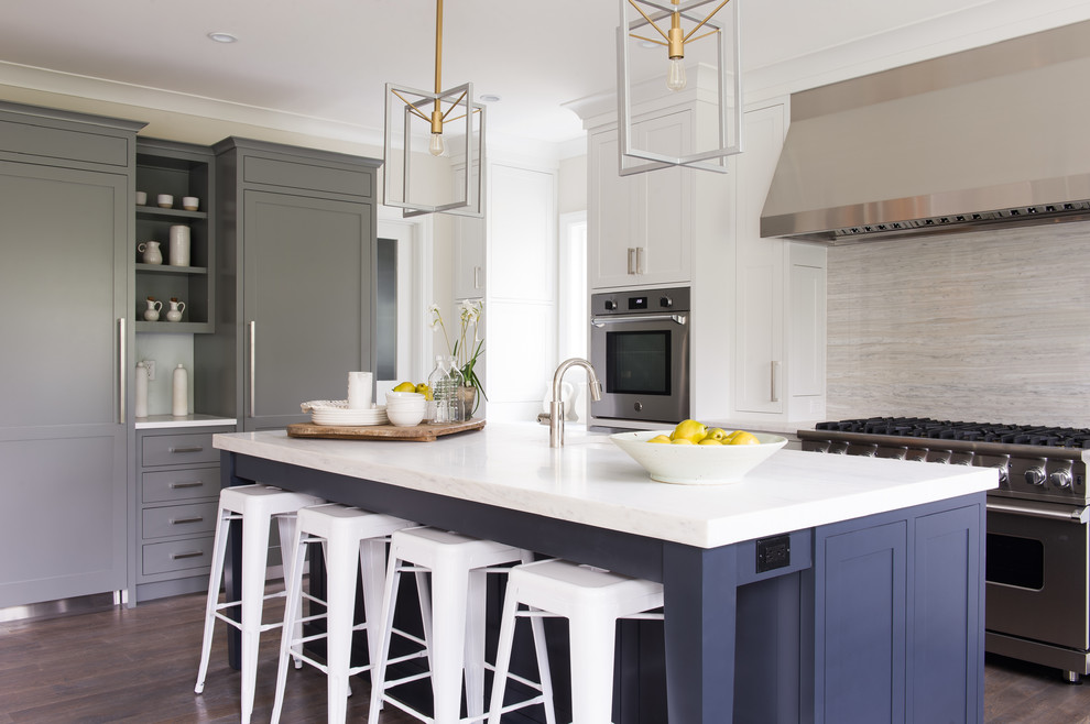 Foto di un cucina con isola centrale costiero con ante in stile shaker, ante blu, paraspruzzi grigio, elettrodomestici in acciaio inossidabile, parquet scuro, pavimento marrone e top bianco