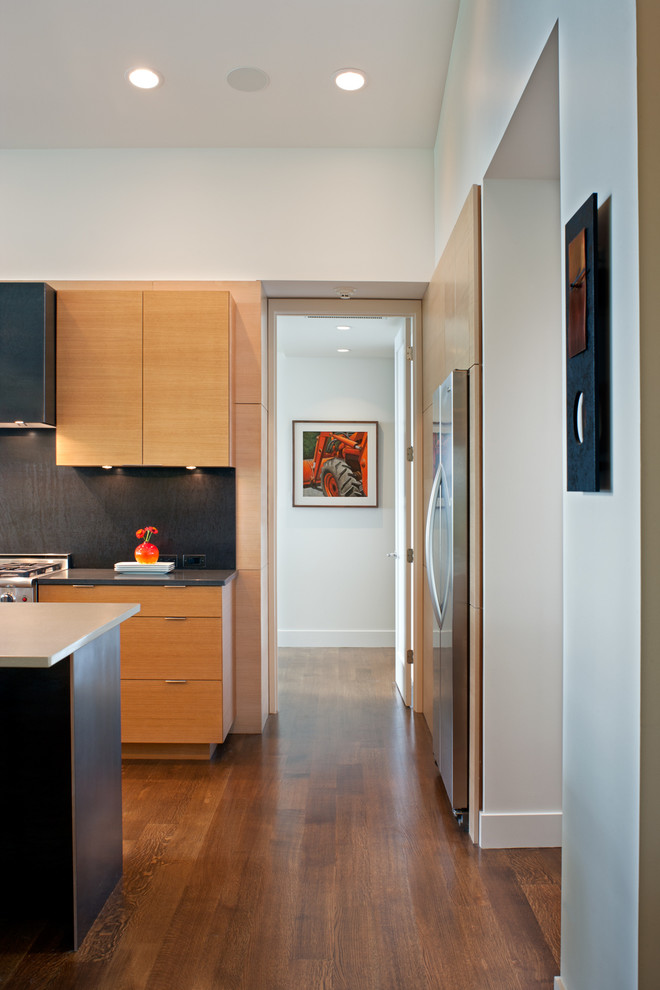 Eat-in kitchen - mid-sized contemporary galley dark wood floor and brown floor eat-in kitchen idea in Charlotte with flat-panel cabinets, light wood cabinets, stainless steel appliances, an island, solid surface countertops and black backsplash
