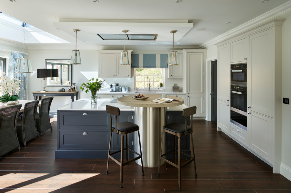 Immagine di una grande cucina chic con ante in stile shaker, lavello sottopiano, ante bianche, paraspruzzi bianco, elettrodomestici neri, pavimento marrone e top bianco