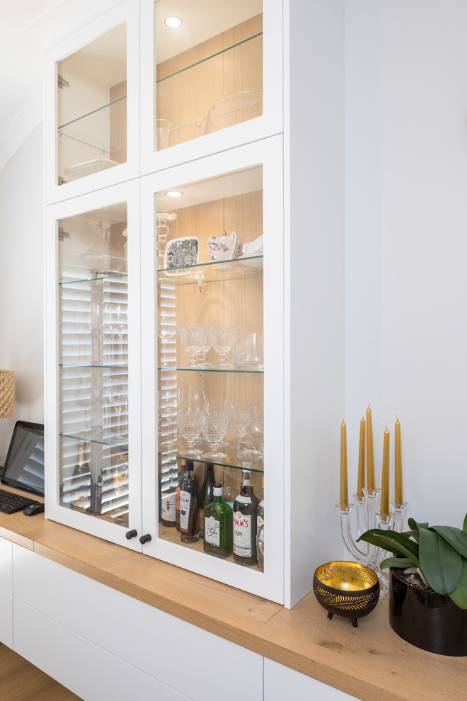 Cette photo montre une cuisine moderne avec un placard à porte plane, des portes de placard blanches et un plan de travail en bois.