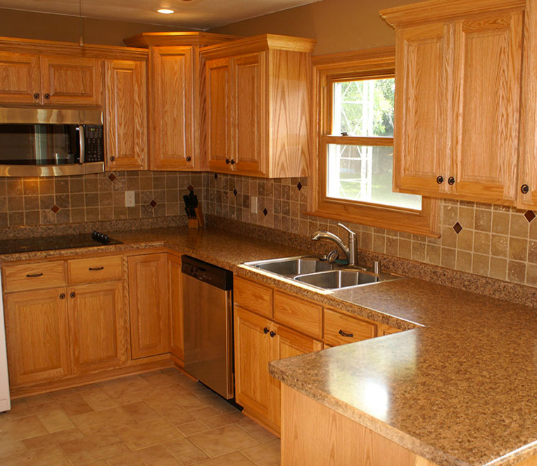 This is an example of a large traditional u-shaped kitchen/diner in Milwaukee with a double-bowl sink, raised-panel cabinets, medium wood cabinets, granite worktops, beige splashback, stone tiled splashback, stainless steel appliances, cement flooring, a breakfast bar and beige floors.