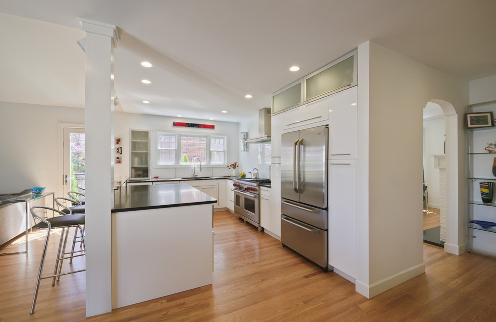 Exempel på ett stort modernt kök, med rostfria vitvaror, släta luckor, vita skåp, granitbänkskiva, glaspanel som stänkskydd, en undermonterad diskho, ljust trägolv och en köksö