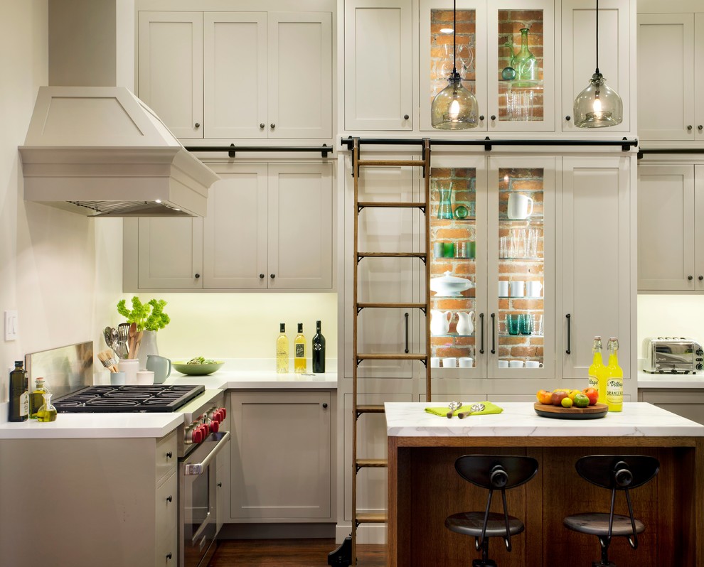 Immagine di una cucina chic con ante di vetro, ante beige, elettrodomestici in acciaio inossidabile e pavimento in legno massello medio