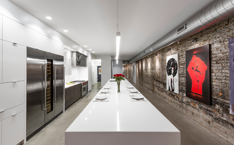 Photo of a large urban kitchen in Cincinnati with flat-panel cabinets, white cabinets, white splashback, glass sheet splashback, stainless steel appliances, concrete flooring, an island, grey floors, a single-bowl sink and engineered stone countertops.