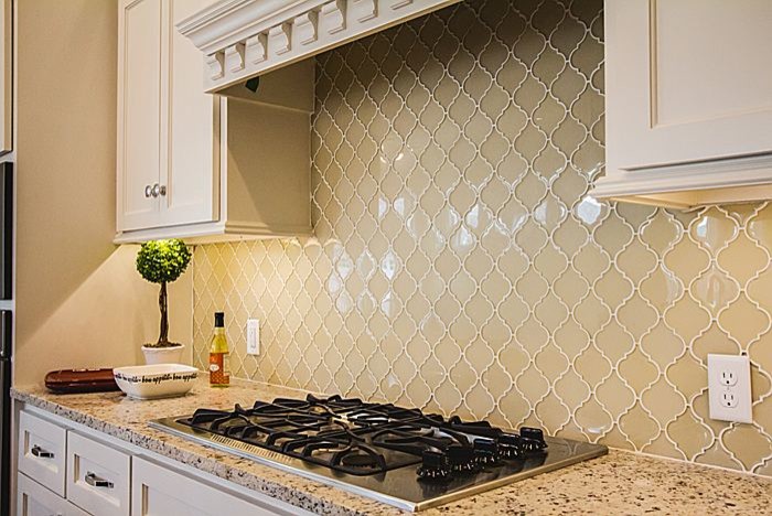 Large arts and crafts l-shaped light wood floor open concept kitchen photo in Oklahoma City with a farmhouse sink, white cabinets, quartzite countertops, beige backsplash, stainless steel appliances and an island