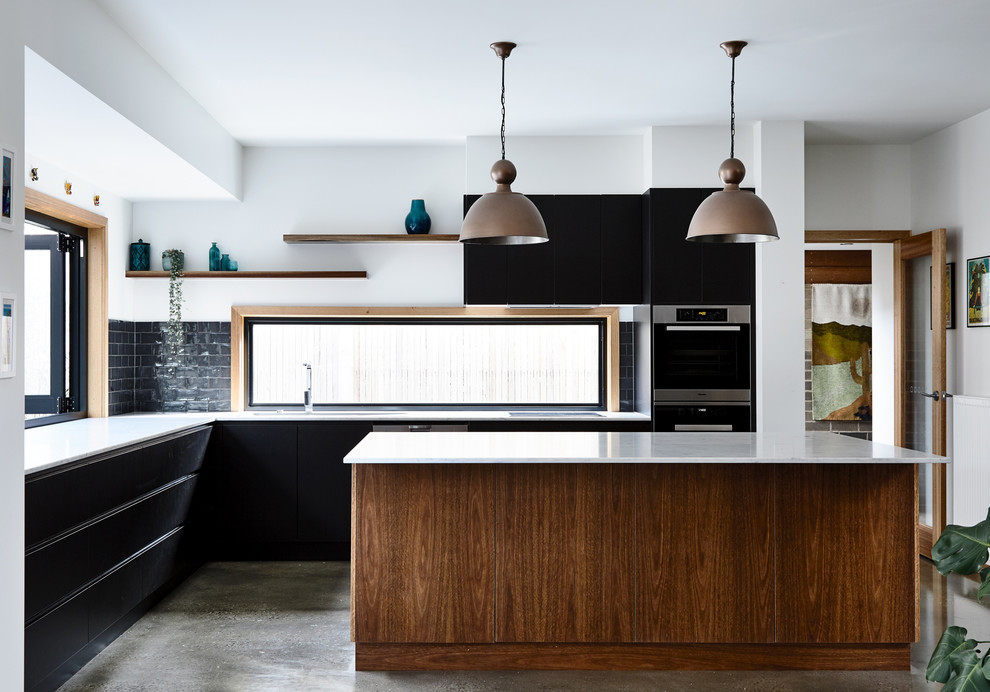 Foto de cocina contemporánea con armarios con paneles lisos, salpicadero de vidrio, suelo de cemento, una isla, suelo gris y con blanco y negro