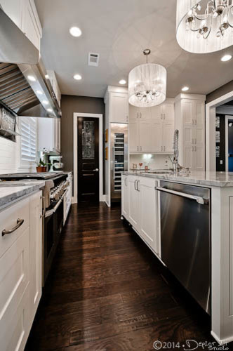 Example of a classic u-shaped dark wood floor eat-in kitchen design in New York with an undermount sink, flat-panel cabinets, white cabinets, granite countertops, white backsplash, subway tile backsplash, stainless steel appliances and two islands