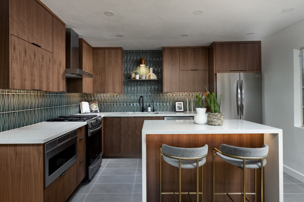 Inspiration for a mid-sized contemporary l-shaped porcelain tile and gray floor enclosed kitchen remodel in Phoenix with an undermount sink, flat-panel cabinets, medium tone wood cabinets, quartz countertops, green backsplash, ceramic backsplash, stainless steel appliances, an island and white countertops
