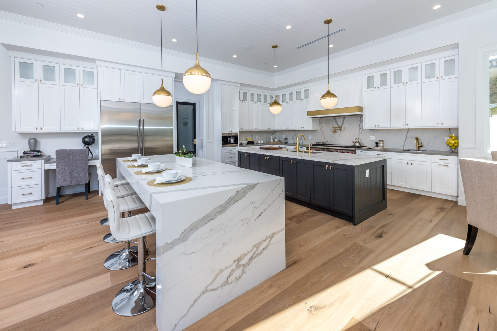 Classic l-shaped kitchen in Los Angeles with shaker cabinets, white cabinets, white splashback, stone slab splashback, stainless steel appliances, medium hardwood flooring, multiple islands, brown floors, grey worktops and a timber clad ceiling.
