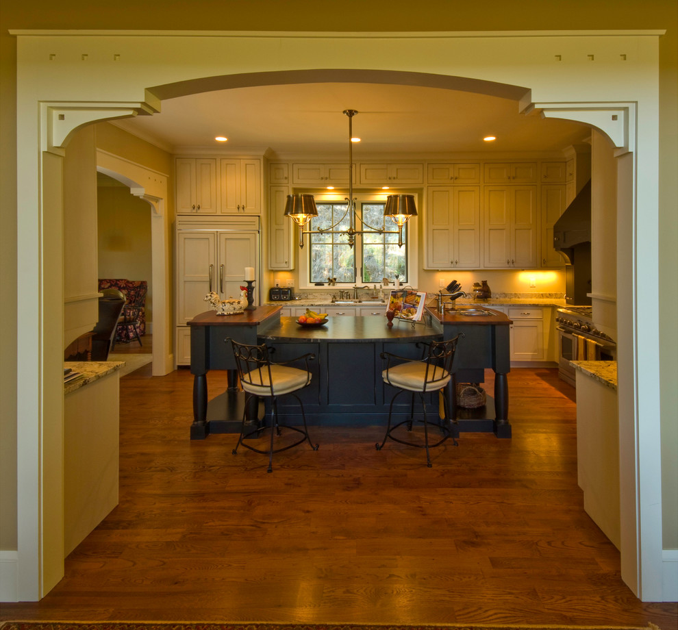 Foto på ett amerikanskt kök, med luckor med infälld panel, beige skåp, ljust trägolv och en köksö