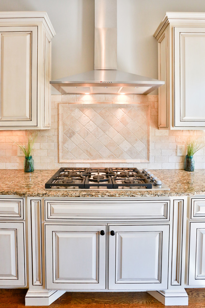 Transitional l-shaped medium tone wood floor eat-in kitchen photo in Nashville with a double-bowl sink, raised-panel cabinets, white cabinets, granite countertops, beige backsplash, porcelain backsplash, stainless steel appliances and an island