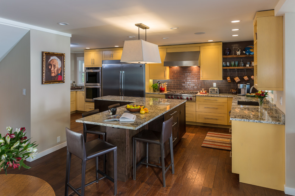 Medium sized midcentury l-shaped open plan kitchen in Seattle with a submerged sink, shaker cabinets, yellow cabinets, engineered stone countertops, red splashback, stainless steel appliances, dark hardwood flooring, an island, brick splashback and brown floors.