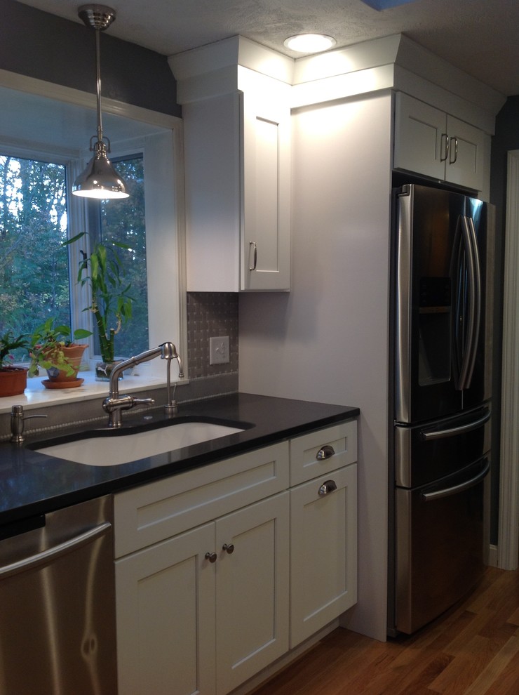Photo of a medium sized traditional galley kitchen in Boston with a submerged sink, shaker cabinets, white cabinets, engineered stone countertops, grey splashback, mosaic tiled splashback, stainless steel appliances, medium hardwood flooring and no island.