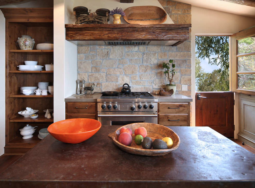 Medium sized mediterranean kitchen in Orange County with dark wood cabinets, stone tiled splashback, stainless steel appliances and an island.