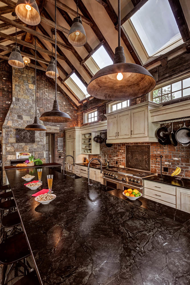 This is an example of a large rustic l-shaped open plan kitchen in Denver with an integrated sink, raised-panel cabinets, beige cabinets, red splashback, brick splashback, integrated appliances, dark hardwood flooring, an island, brown floors and black worktops.