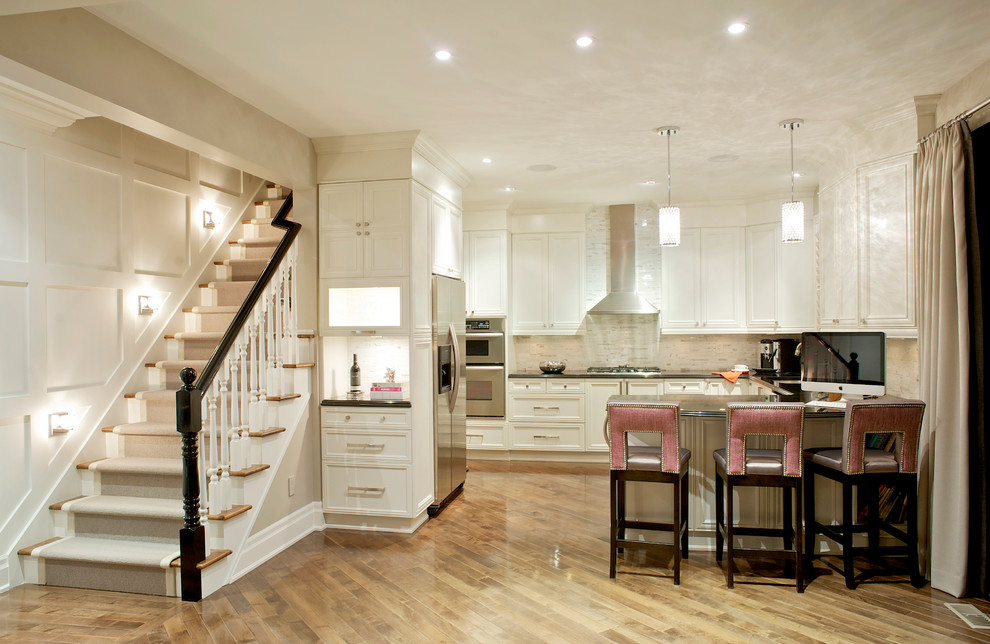 Large transitional u-shaped light wood floor kitchen photo in Toronto with recessed-panel cabinets, white cabinets, beige backsplash, stainless steel appliances, stone tile backsplash and quartz countertops