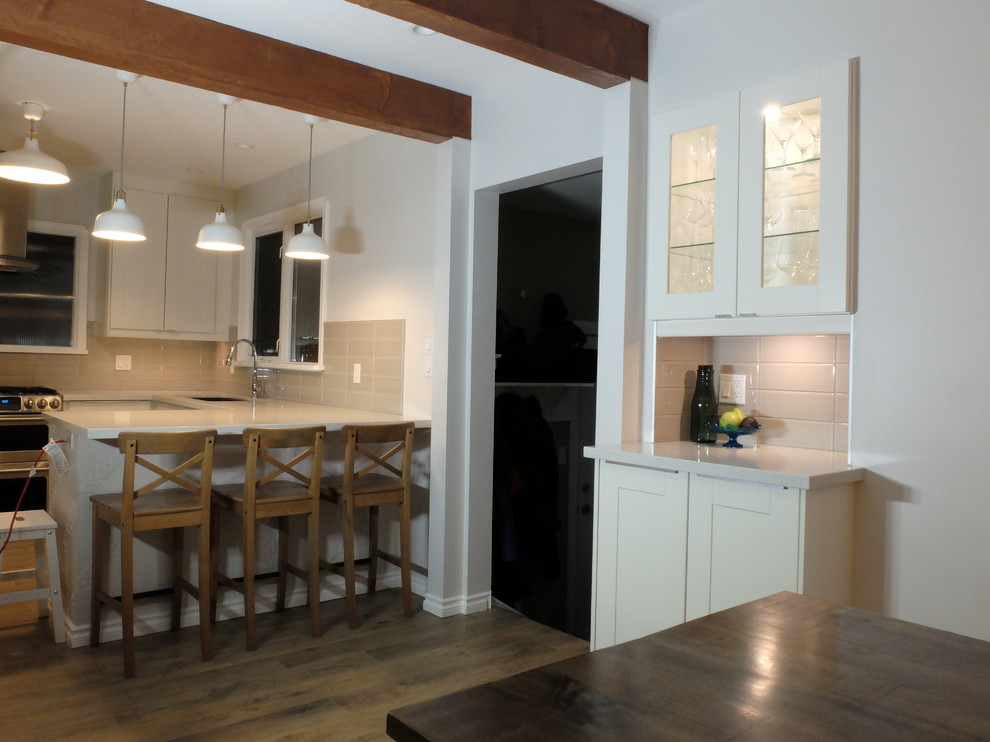 Exempel på ett mellanstort klassiskt kök, med en undermonterad diskho, vita skåp, bänkskiva i kvartsit, grått stänkskydd, stänkskydd i glaskakel, rostfria vitvaror, mellanmörkt trägolv, brunt golv, skåp i shakerstil och en halv köksö