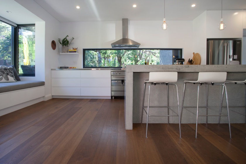 Esempio di un cucina con isola centrale minimal con top in cemento e pavimento in legno massello medio