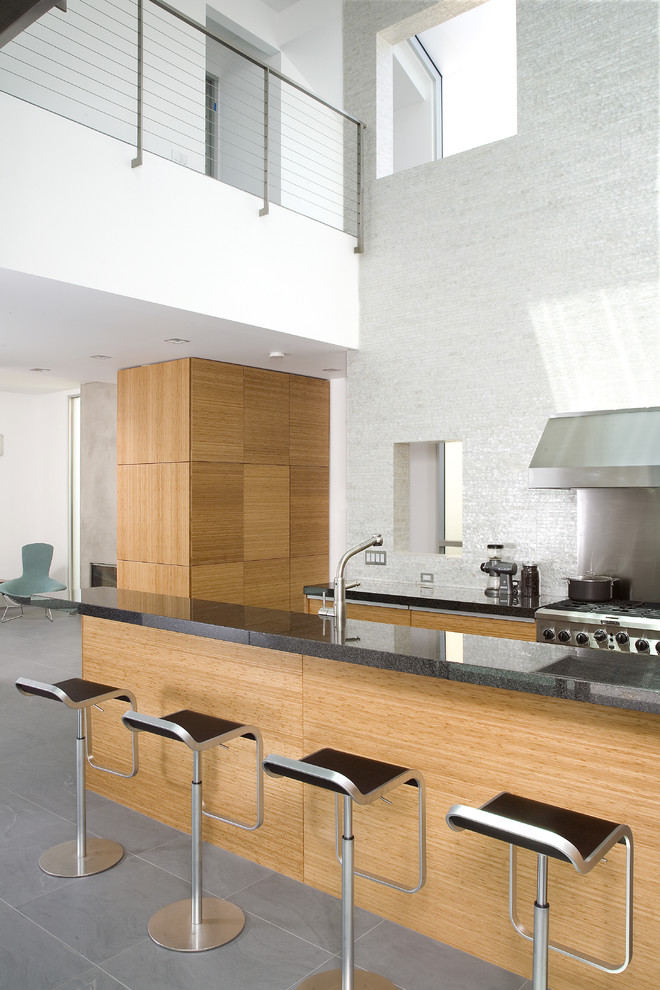 На фото: кухня в стиле модернизм с техникой из нержавеющей стали, плоскими фасадами, светлыми деревянными фасадами и белым фартуком
