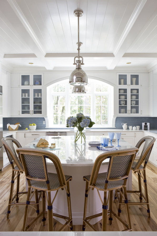 Example of a large beach style u-shaped light wood floor eat-in kitchen design in DC Metro with glass-front cabinets, marble countertops, blue backsplash, stainless steel appliances, an island, white cabinets and subway tile backsplash