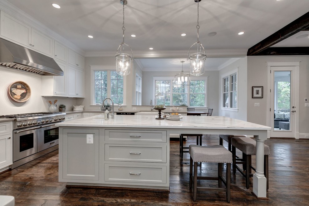 Example of a large cottage u-shaped dark wood floor open concept kitchen design in DC Metro with a farmhouse sink, shaker cabinets, white cabinets, quartzite countertops, white backsplash, stainless steel appliances and an island