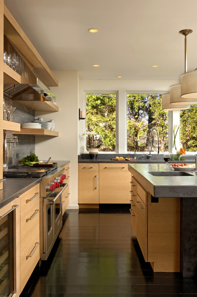 Bild på ett mellanstort funkis kök, med släta luckor, skåp i ljust trä, granitbänkskiva, rostfria vitvaror, en köksö, en integrerad diskho, mörkt trägolv, stänkskydd med metallisk yta och stänkskydd i metallkakel
