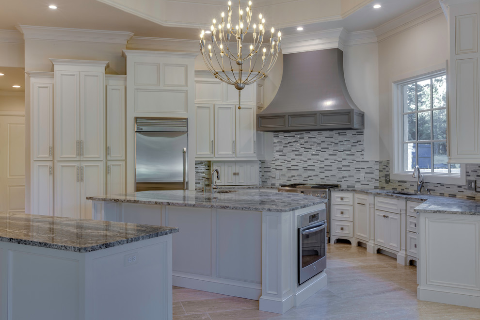 Inspiration for a traditional u-shaped kitchen/diner in Oklahoma City with a built-in sink, beaded cabinets, white cabinets, granite worktops, multi-coloured splashback, glass tiled splashback, stainless steel appliances and multiple islands.