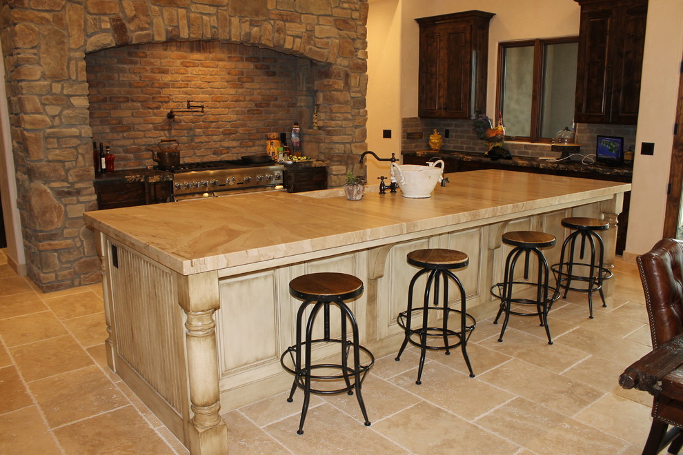 Inspiration for a large mediterranean l-shaped travertine floor and beige floor eat-in kitchen remodel in San Luis Obispo with a farmhouse sink, beaded inset cabinets, distressed cabinets, marble countertops, stainless steel appliances, an island, gray backsplash and stone tile backsplash