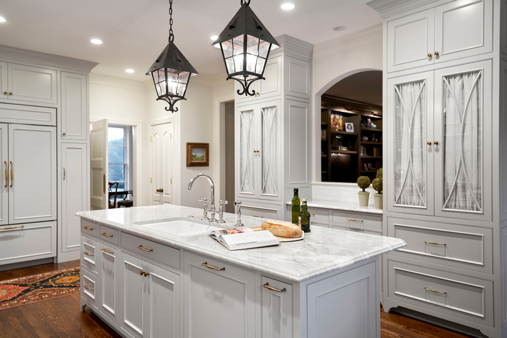 Mid-sized transitional galley dark wood floor and brown floor enclosed kitchen photo in Nashville with an undermount sink, shaker cabinets, white cabinets, quartzite countertops, white backsplash, porcelain backsplash, stainless steel appliances, an island and white countertops