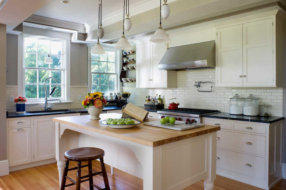 Eat-in kitchen - mid-sized country l-shaped light wood floor eat-in kitchen idea in Boston with an undermount sink, raised-panel cabinets, white cabinets, white backsplash, subway tile backsplash, stainless steel appliances, an island and granite countertops