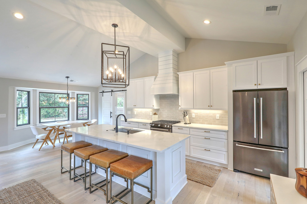 Transitional galley light wood floor and beige floor eat-in kitchen photo in Charleston with an undermount sink, shaker cabinets, white cabinets, gray backsplash, subway tile backsplash, stainless steel appliances, an island and white countertops